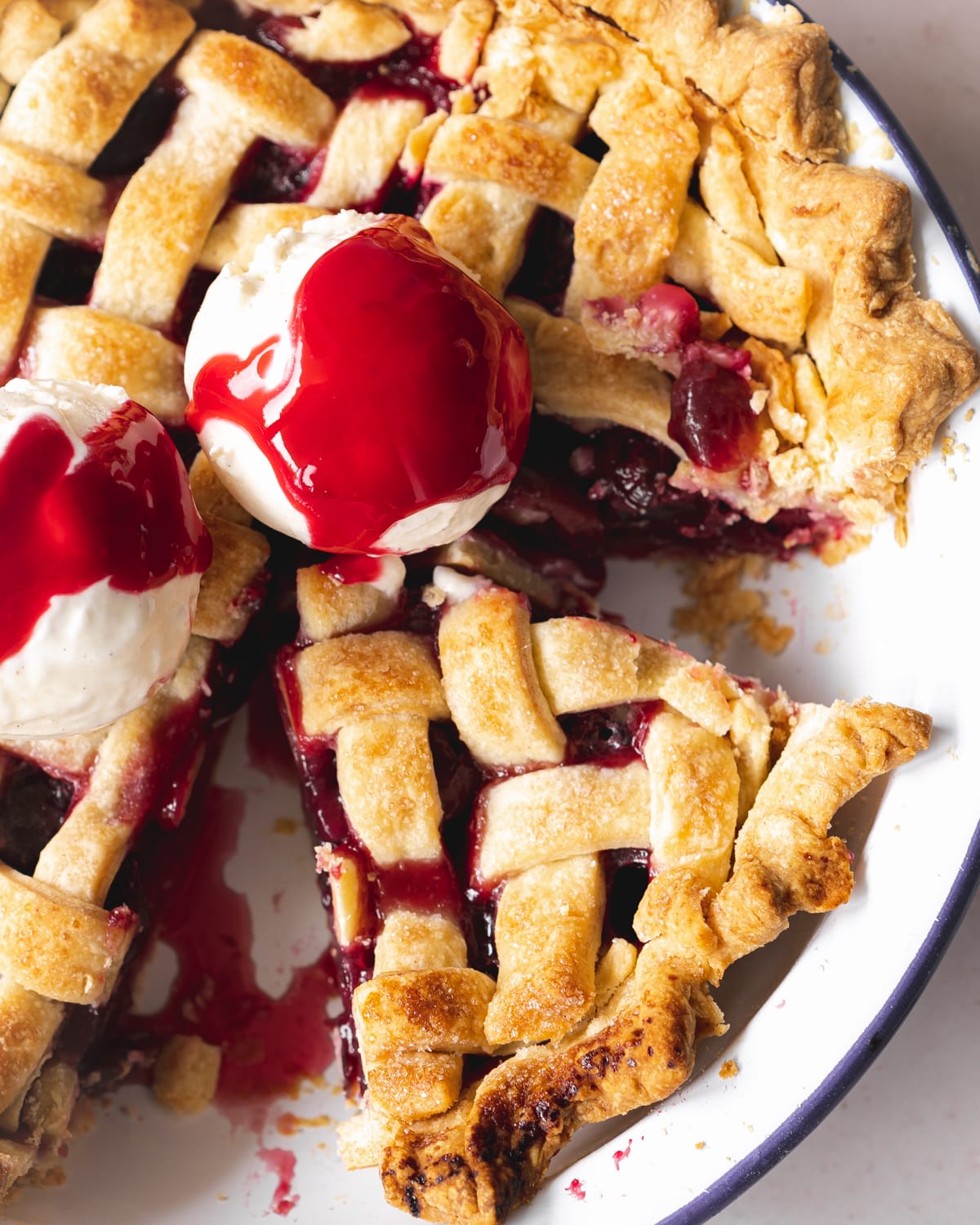 vegan cherry pie with lattice top and ice cream scoops on top.