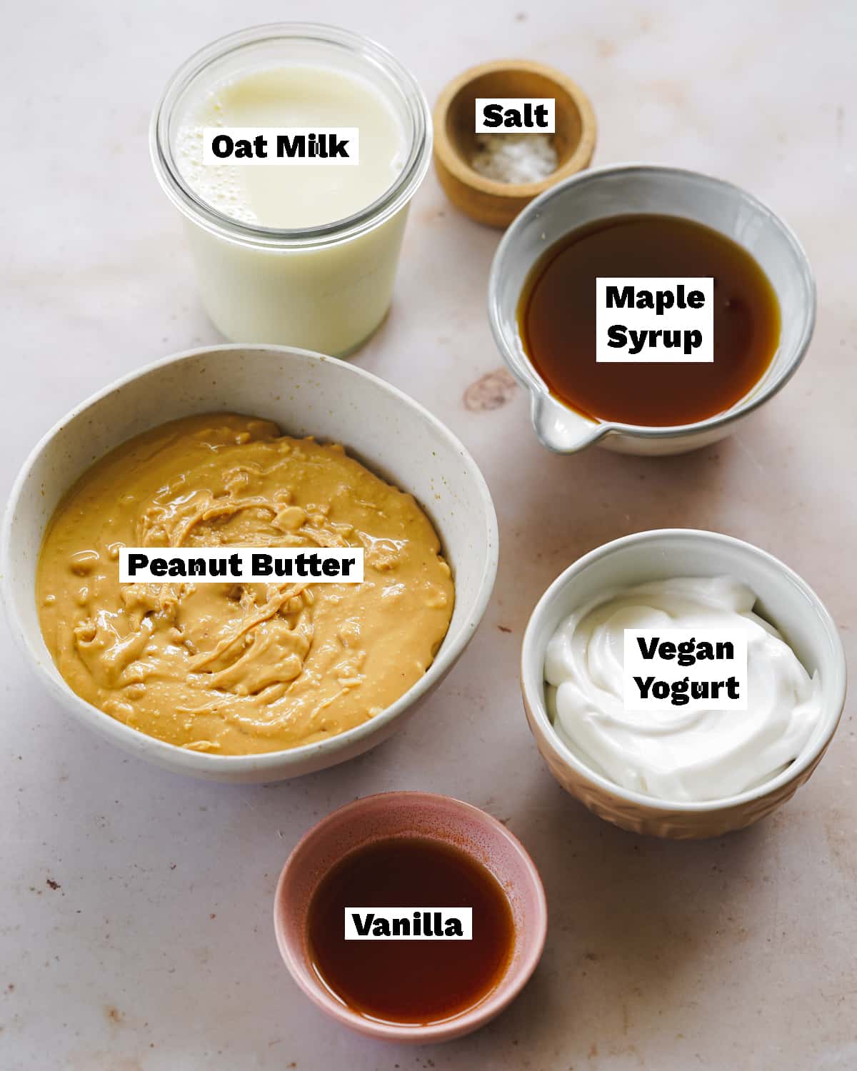 ingredients for peanut butter ice cream measured out in bowls on a pink surface.