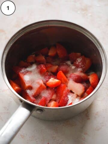 quartered strawberries in a saucepan sprinkled with sugar.