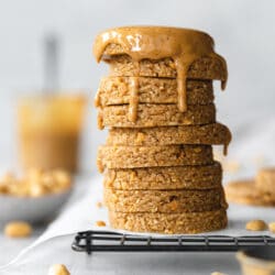 stack of peanut butter cookies with peanut butter dripping over the top on a cooling rack.