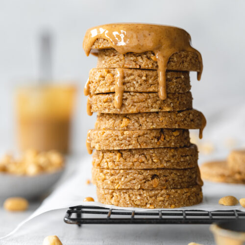 stack of peanut butter cookies with peanut butter dripping over the top on a cooling rack.