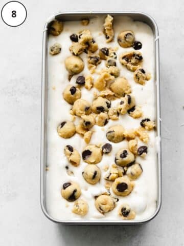 vegan cookie dough ice cream in a loaf pan with roughly chopped cookie dough chunks on top.