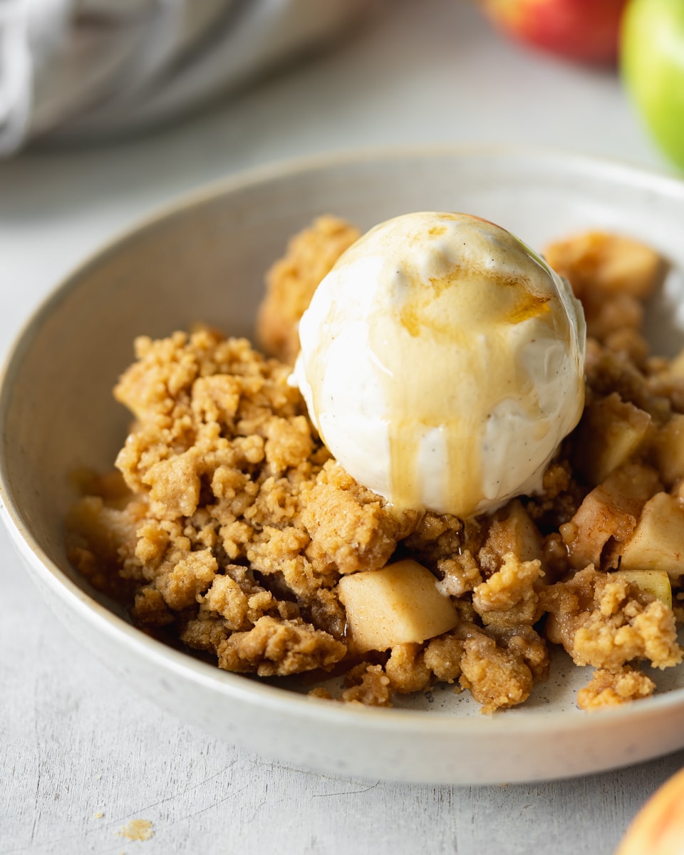 apple crumble with a scoop of vanilla ice cream in a bowl.
