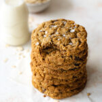 stack of oatmeal raisin cookies with a small jug of oat milk.