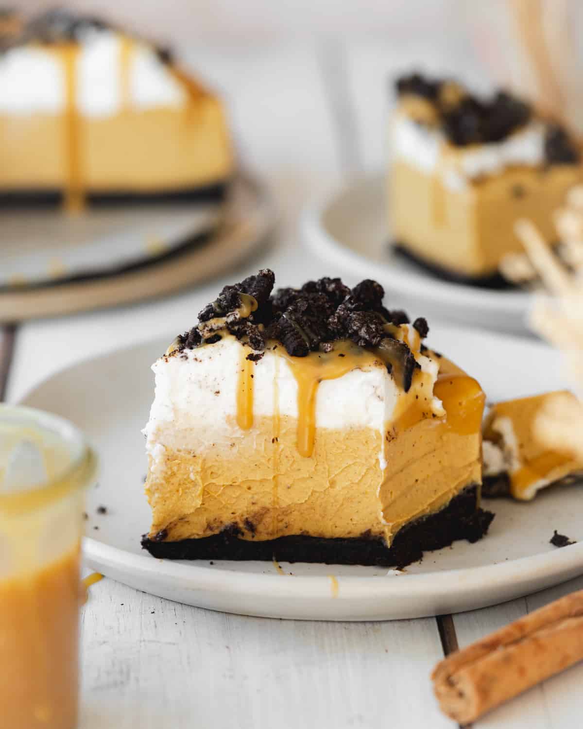 a slice of pumpkin cheesecake with caramel sauce and oreos on top on a plate.