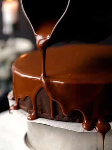 pouring thick chocolate glaze over a no bake chocolate biscuit cake.