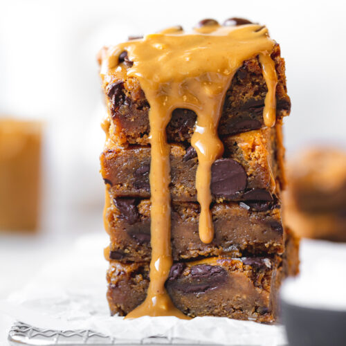 stack of blondies with chocolate chips and peanut butter melted over them.