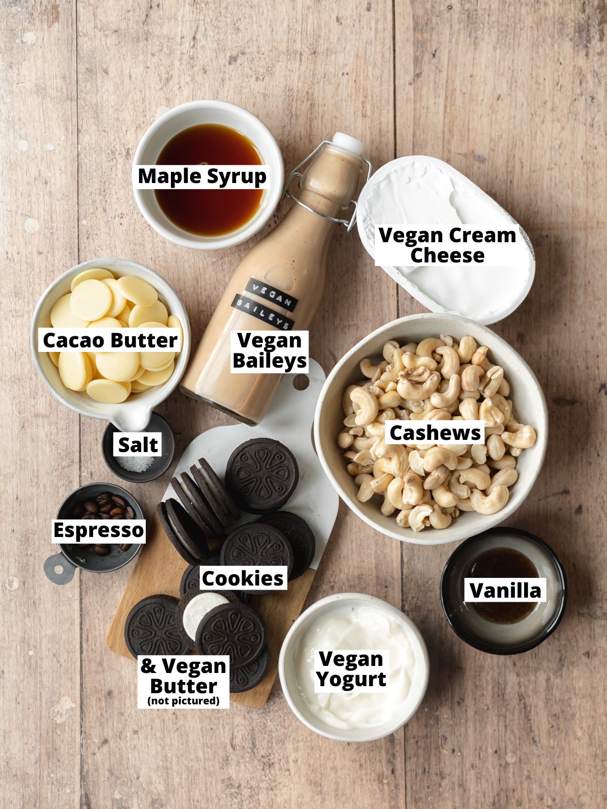 ingredients for dairy free baileys cheesecake measured out in bowls on a wooden surface.