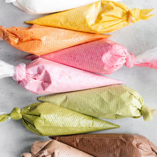 pink, green, yellow, orange, brown and white royal icing in piping bags.