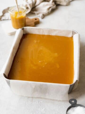 shortbread and caramel layered in a tray lined with parchment paper.
