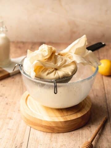 a cheesecloth with homemade mascarpone sitting on top of a bowl.