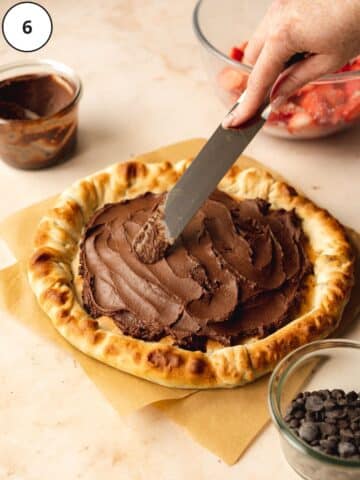 spreading nutella on top of a baked pizza base.