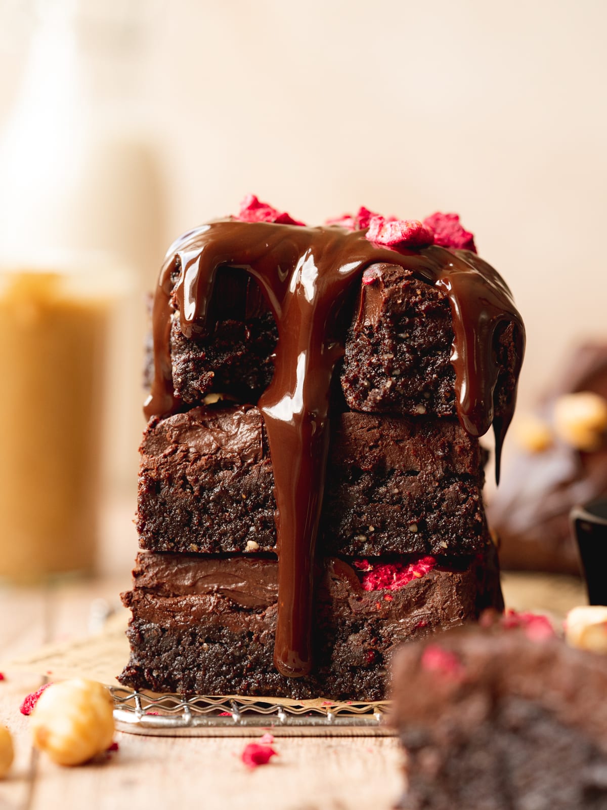 a stack of fudgy no bake brownies with ganache and ganache poured on top of them.