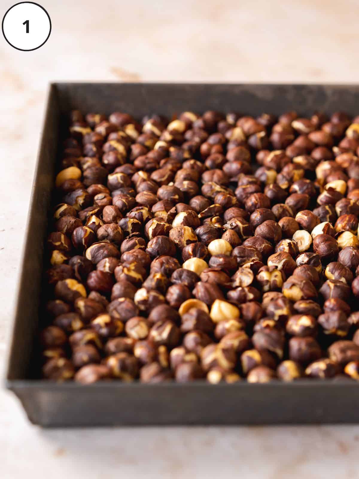 roasted hazelnuts with skins on a baking sheet.