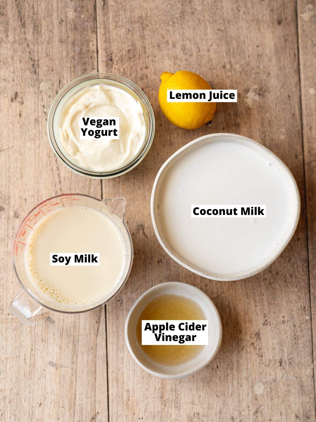 ingredients for vegan mascarpone cheesecake measured out in bowls on a wooden surface.