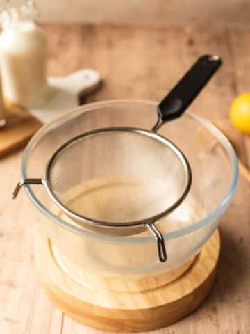 a clear bowl with a fine-mesh sieve on top.