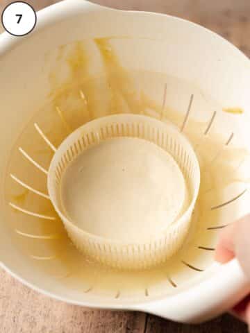vegan ricotta cheese in a cheese mold on top of a colander.