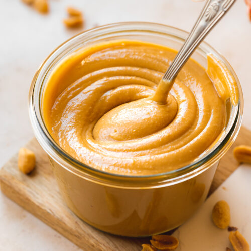 a weck jar with creamy peanut butter and a spoon showing the thick consistency.