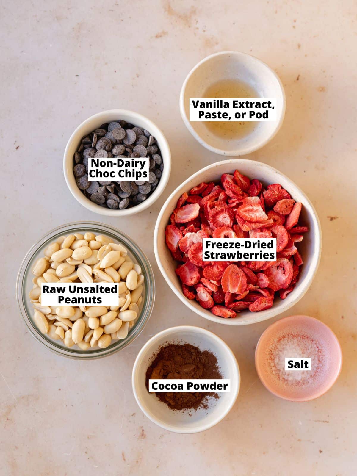 overhead shot of ingredients needed to make 3 flavors of homemade gourmet peanut butter (plain, chocolate, and strawberry) measured out into bowls and labeled with text overlay.