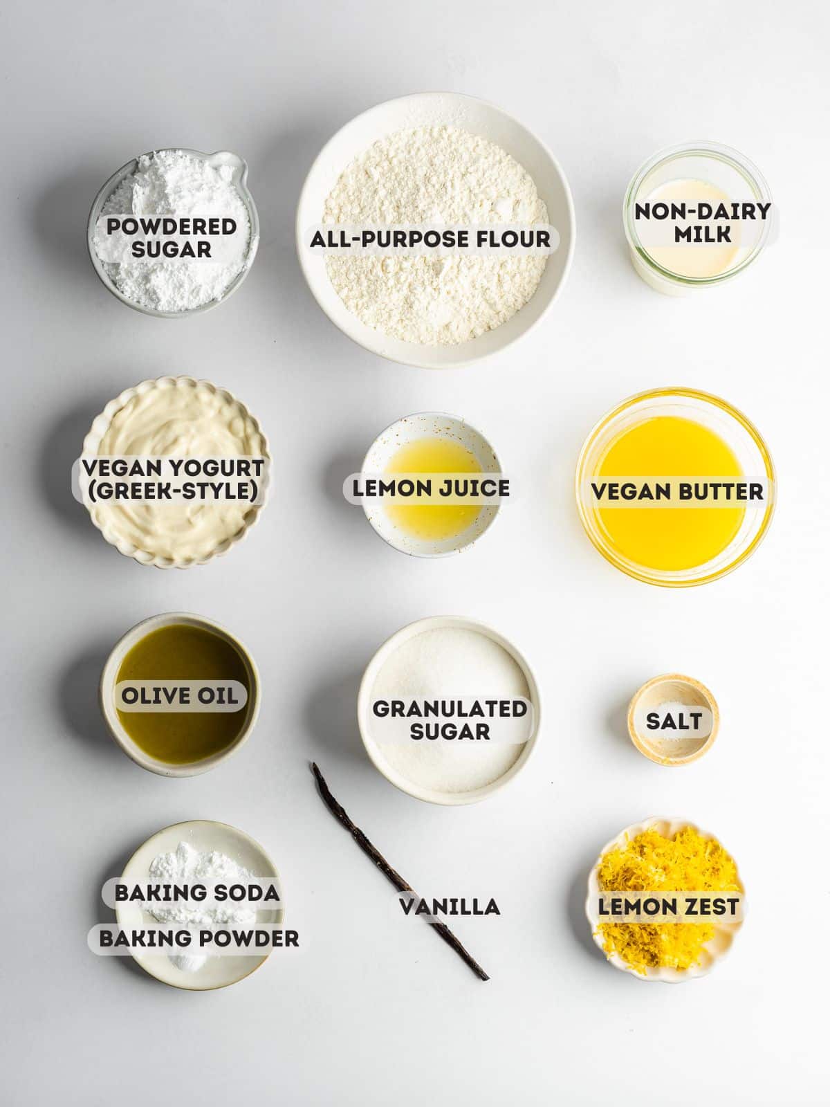 ingredients needed to make vegan lemon loaf measured out into bowls on a gray table.