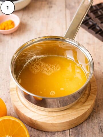 Freshly squeezed orange juice being reduced in a pan.