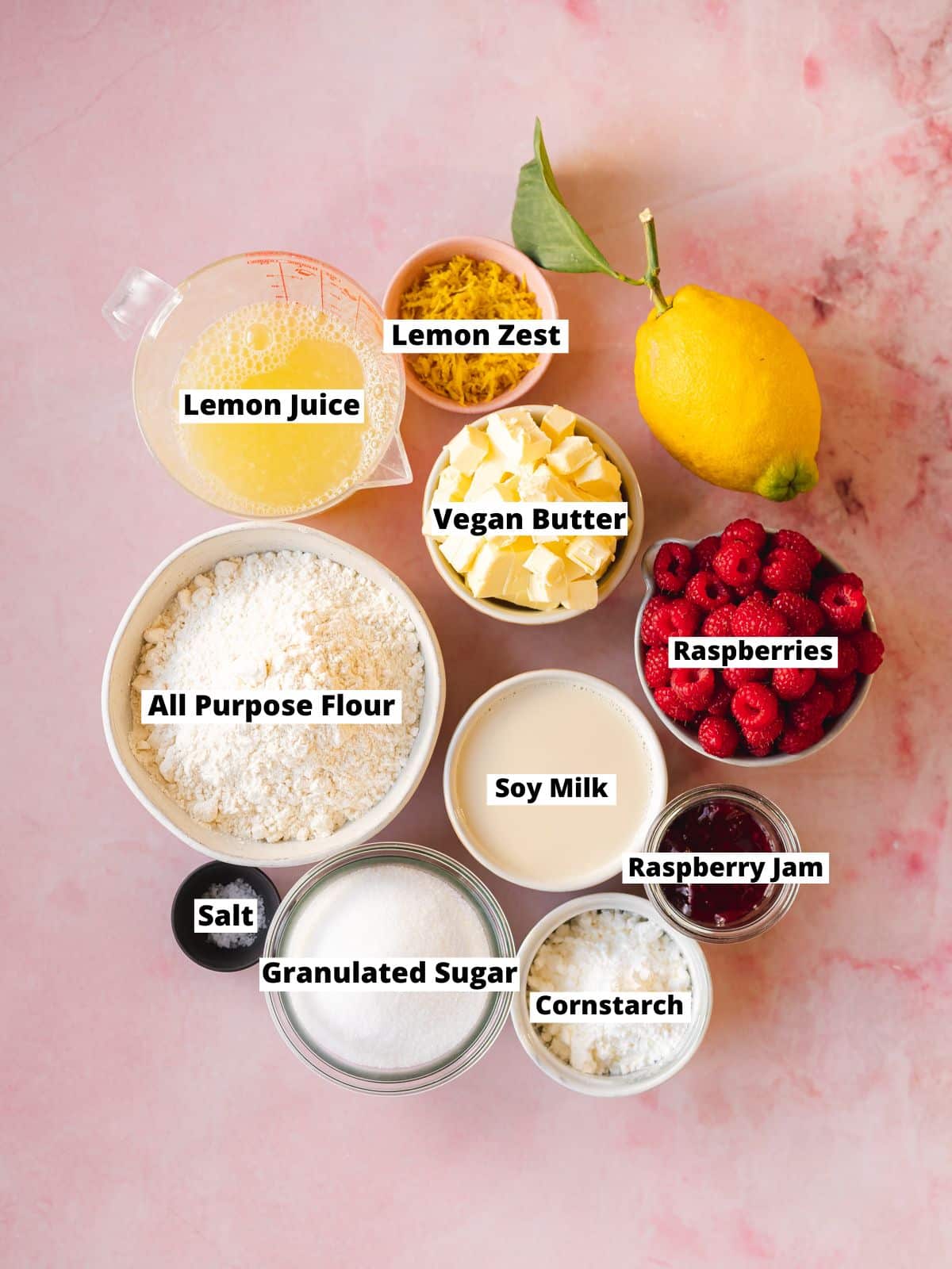 Ingredients needed for making plant-based mini lemon tarts measured out into bowls on a pink background with text overlay.