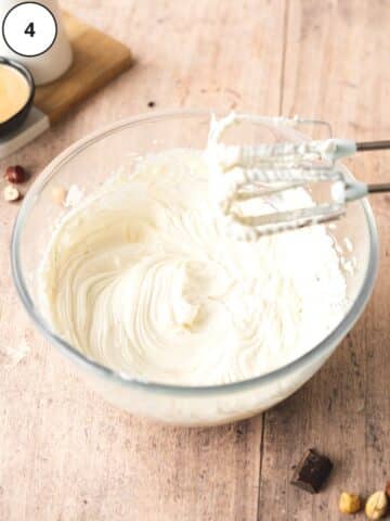 Cream cheese and yogurt mixed together in a clear mixing bowl.
