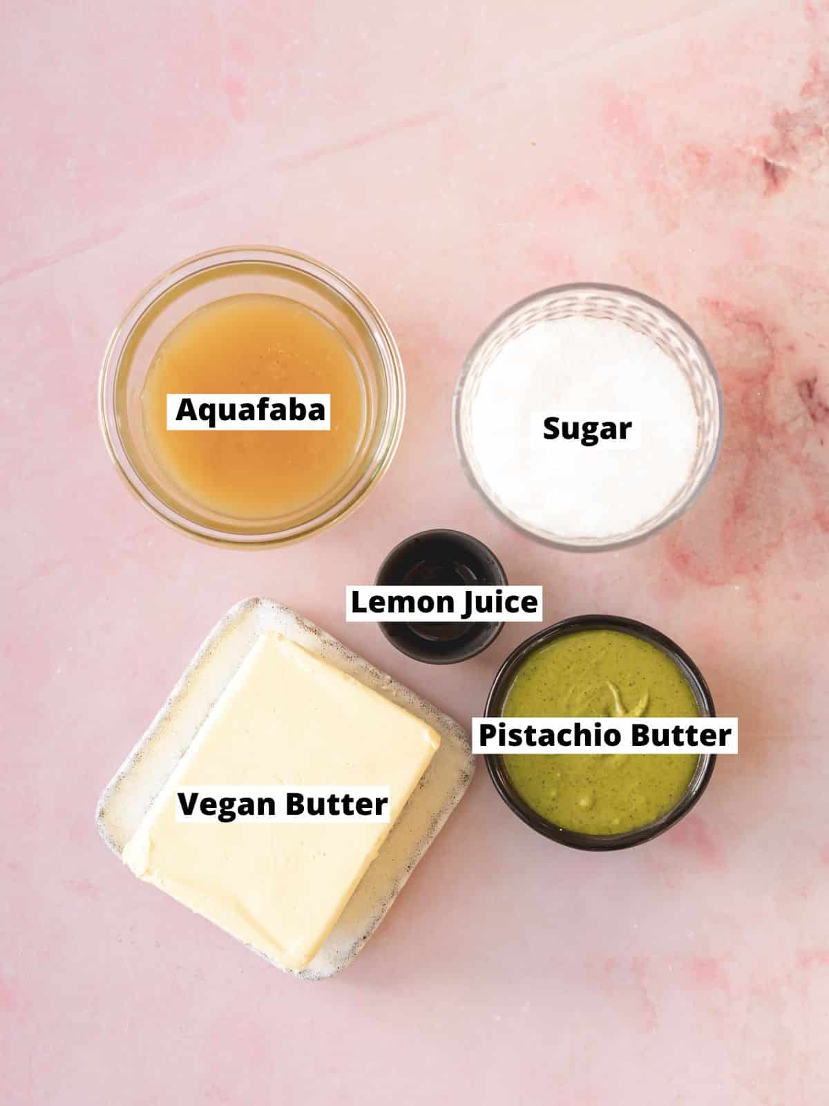 ingredients for vegan pistachio frosting measured out in bowls on top of a pink marble surface.
