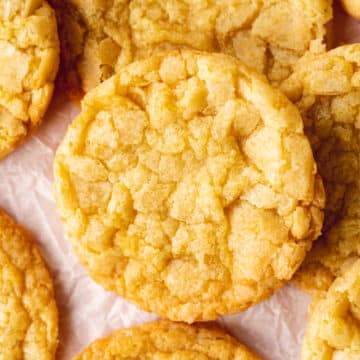 hero shot of a vegan lemon crinkle cookie showing the crunchy and chewy texture, on crunched up baking paper.