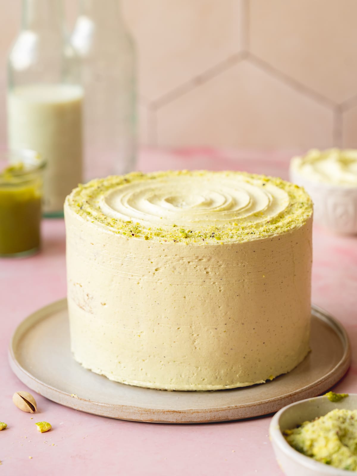 vegan pistachio cake coated in easy pistachio buttercream frosting on a ceramic plate.