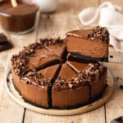 Hero shot of a slice of vegan chocolate cheesecake being removed from the serving platter with a pie server.