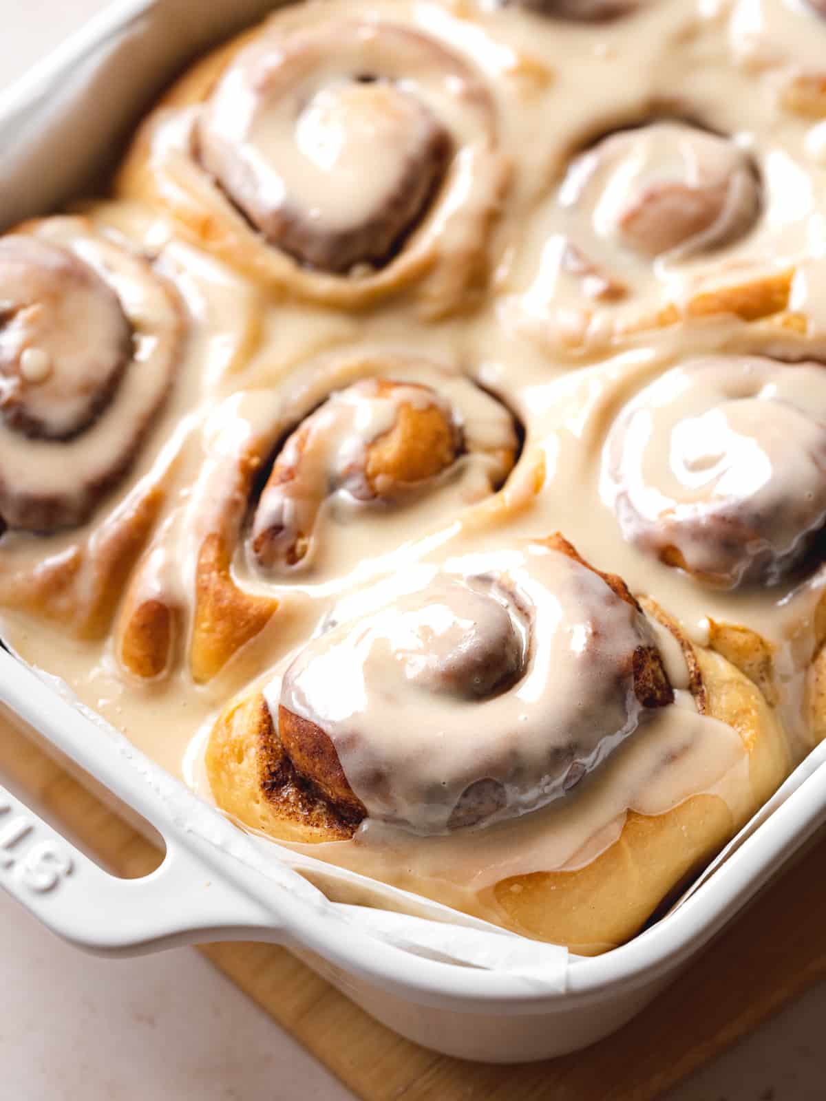 45 degree angle shot of a white 9x13 staub baking dish with a batch of vegan cinnamon buns.
