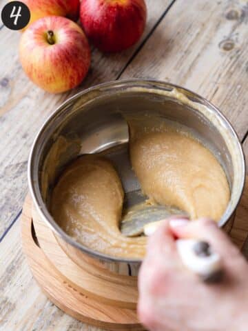 apple curd thats been cooked in a saucepan with a spatula showing the thick consistency.