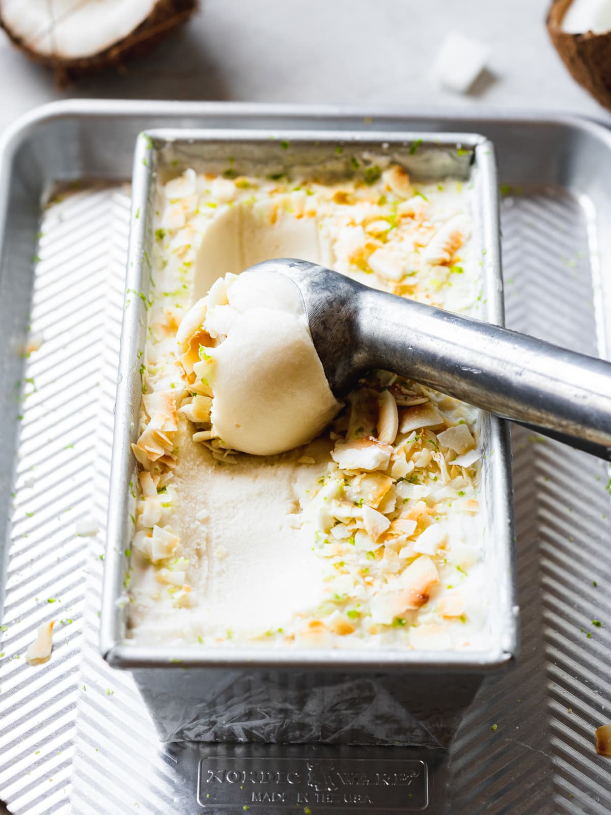 homemade coconut milk sorbet in a laof pan with freshly grated lime zest and coconut chips.