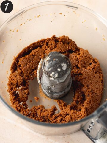 Biscoff cookie crust mixture in the base of a food processor.