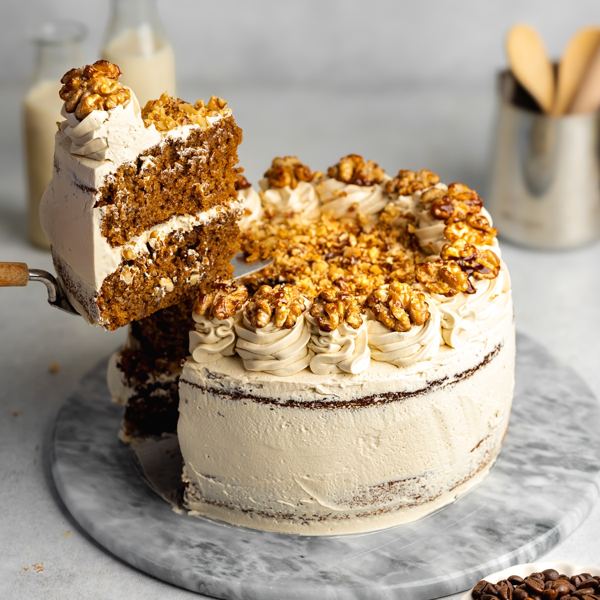 a two-tier coffee walnut cake with a slice being lifted away with a cake slice.