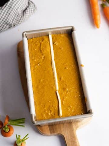 carrot loaf cake with strips of vegan butter placed down the center before baking.