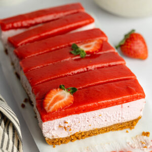 slices of strawberry cheesecake with strawberry curd topping on a serving dish.