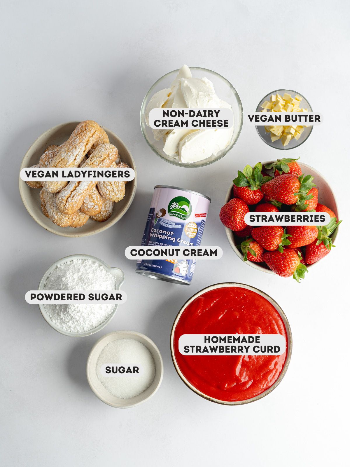 ingredients for vegan charlotte cake measured out in bowls on a gray surface.