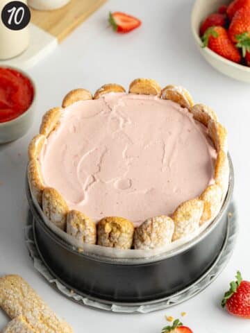 a strawberry charlotte cake in a lined cake pan before going into the fridge to set.