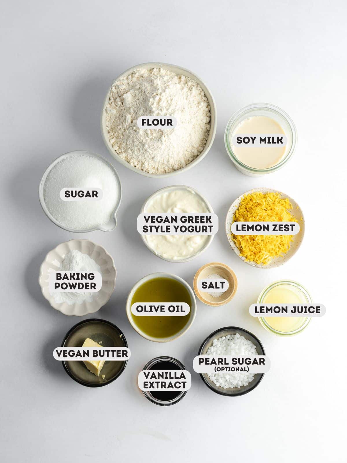 ingredients to make vegan lemon muffins measured out in bowls on a gray surface.