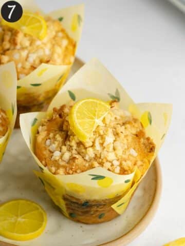 freshly baked lemon muffins in lemon tulip liners on a ceramic plate.