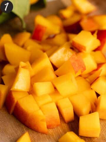 chopped fresh peaches on a wooden cutting board.