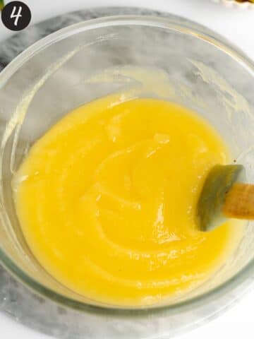 pineapple curd in a large mixing bowl with a rubber spatula.