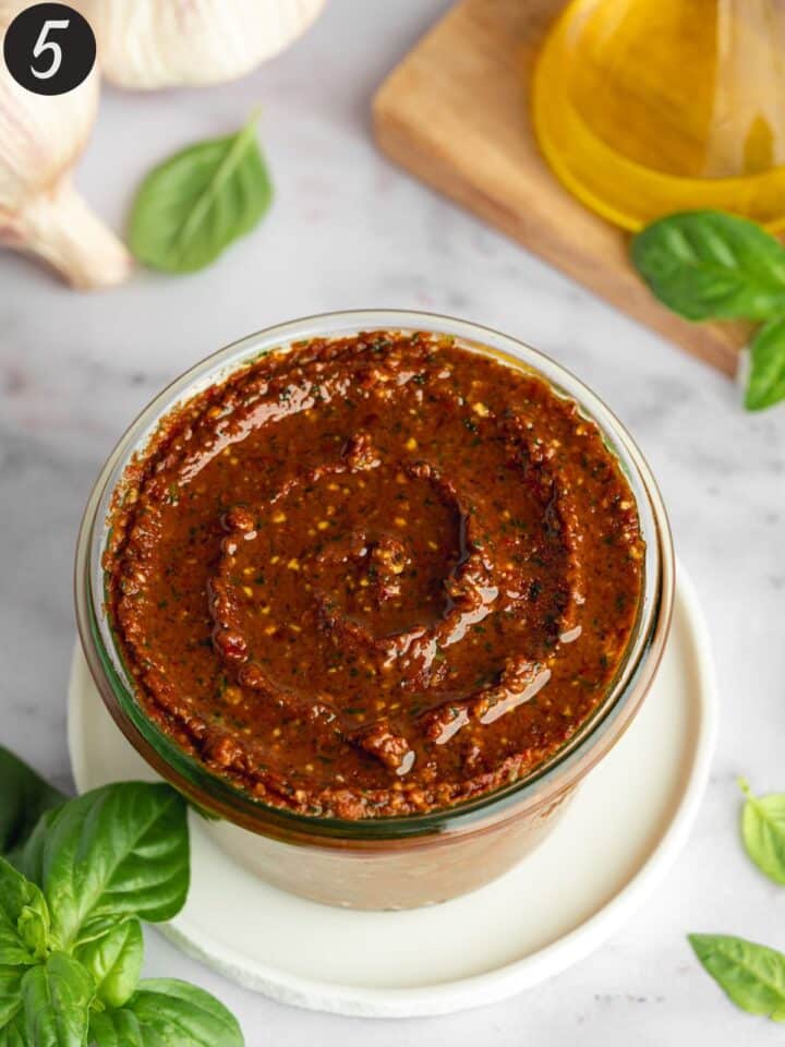 pesto rosso in a glass jar with a thin layer of olive oil drizzled on top before going into the fridge.