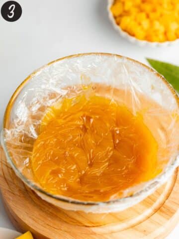 mango curd covered in plastic wrap before chilling.