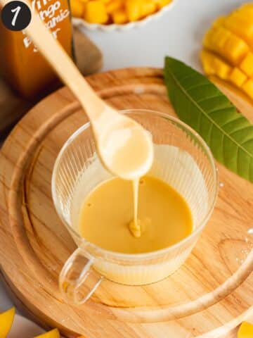 cornstarch and mango balsamic vinegar mixed together in a glass using a small wooden spoon.