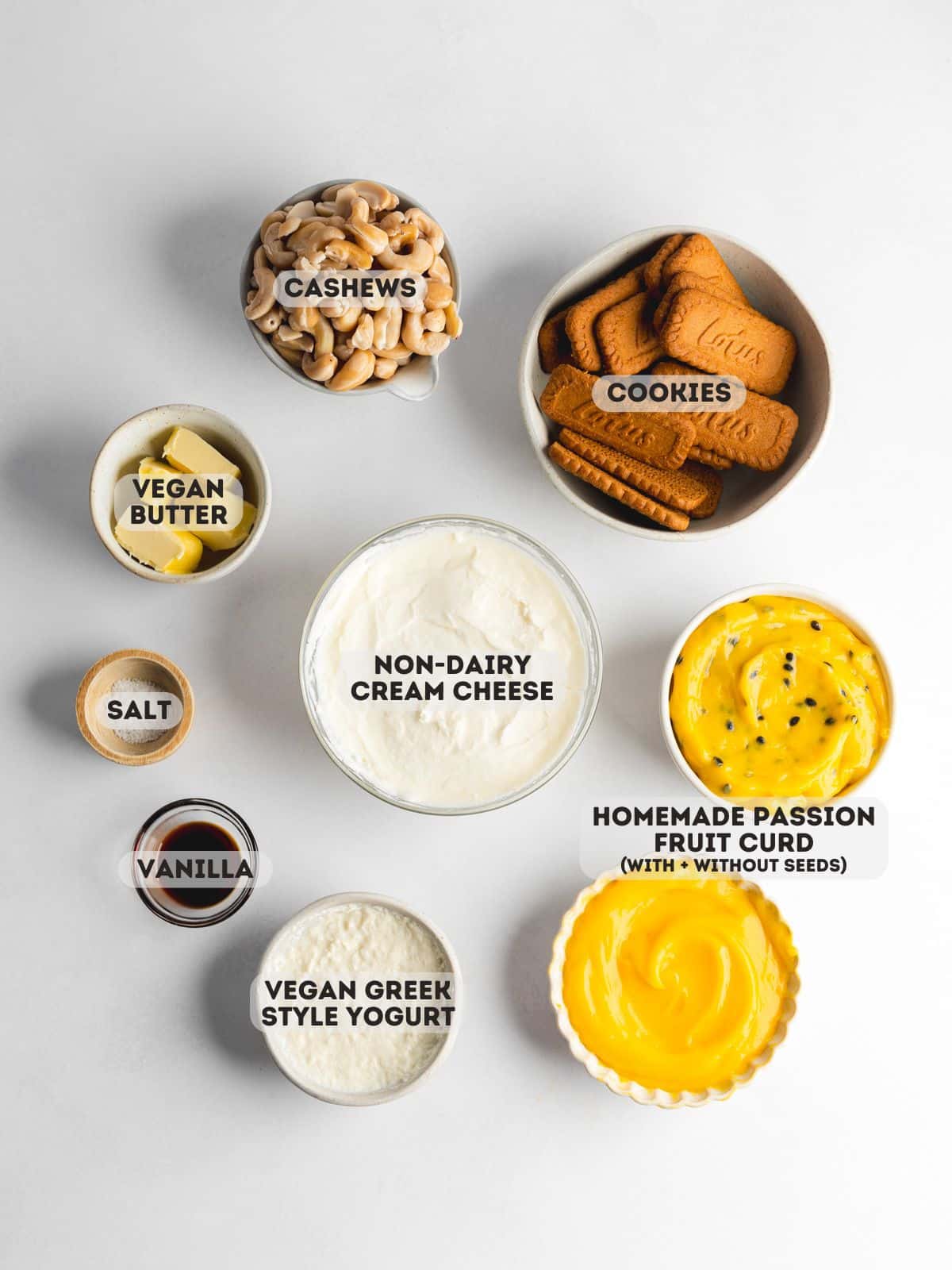 ingredients for vegan passion fruit cheesecake measured out in bowls on a white surface.
