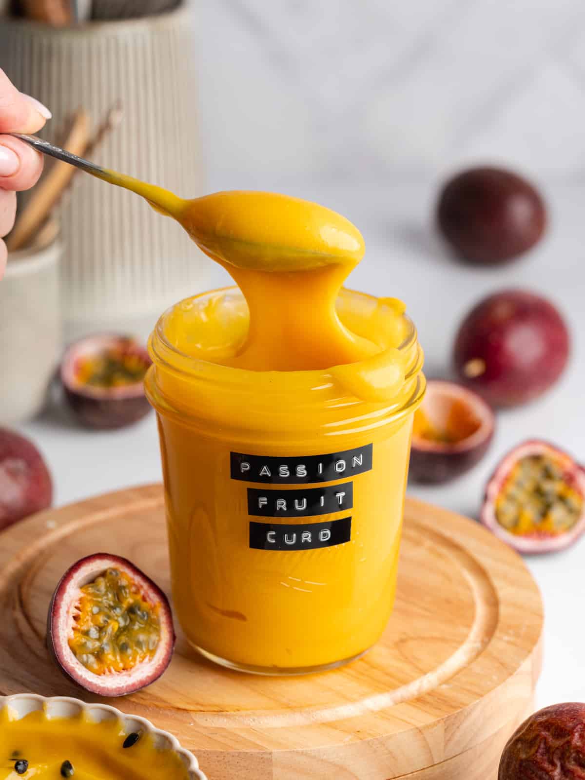 a jar of passion fruit curd with fresh passion fruits scattered around it.