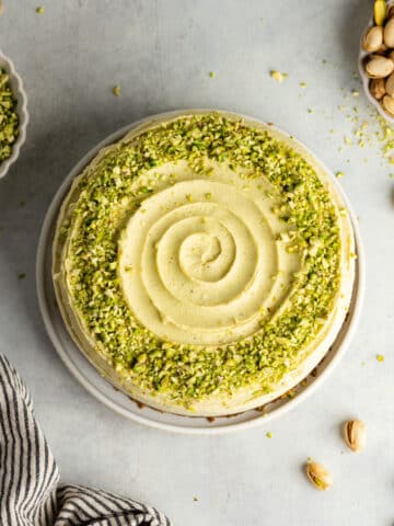 pistachio cheesecake decorated with white chocolate ganache and pistachio pieces.